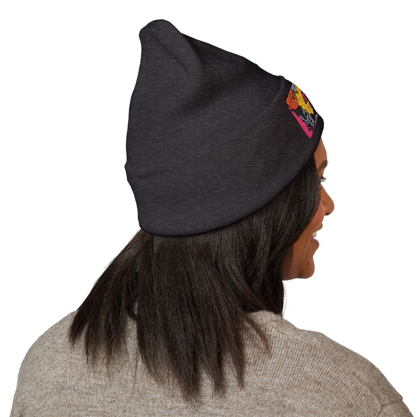 Person wearing a dark gray beanie with colorful designs on a white background